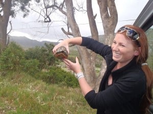 A smiling lady holding holding up a tortoise 
