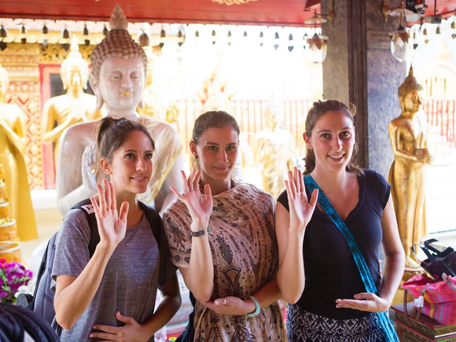 Three ladies doing a hand gesture at a temple