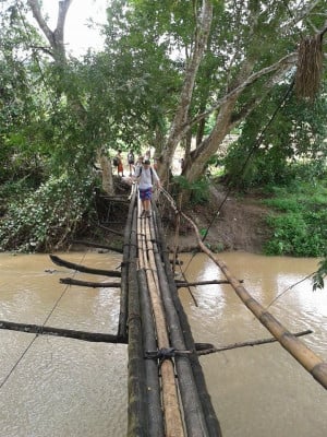 Travellers walking across water on a handmade bridge