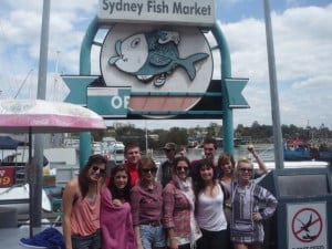 Jenny and fellow travellers in front of the Sydney Fish Market sign