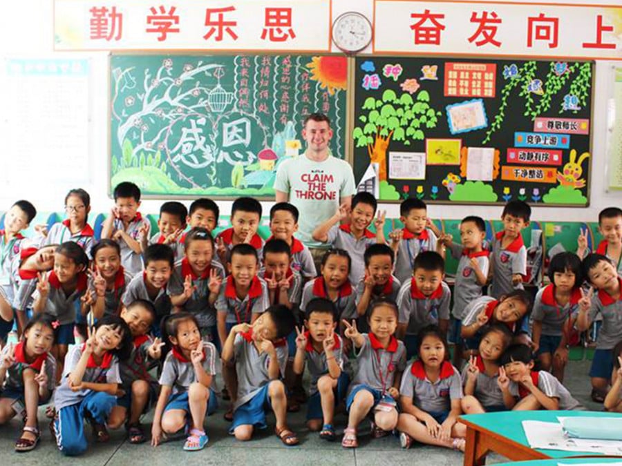 A man posing for a photo with schoolkids in a classroom