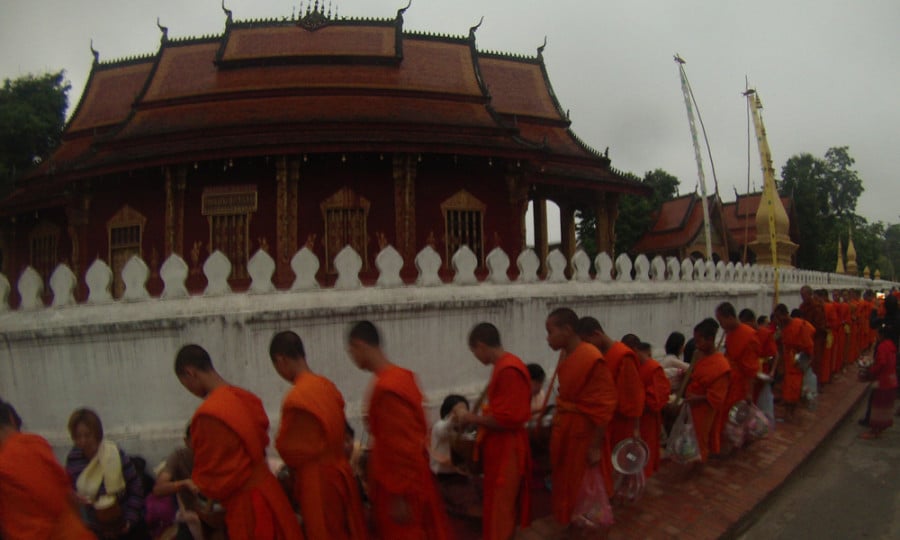 Buddhist monks in orange robes lined up outside a temple