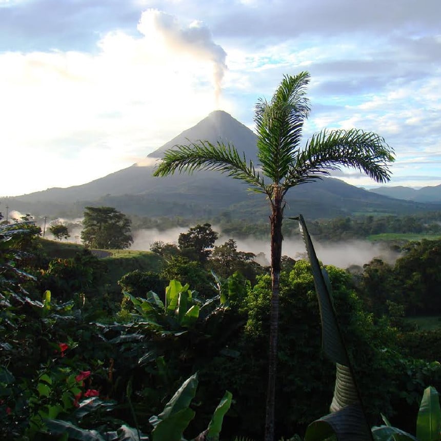 Arenal Volcano with billowing smoke in the middle of jungle