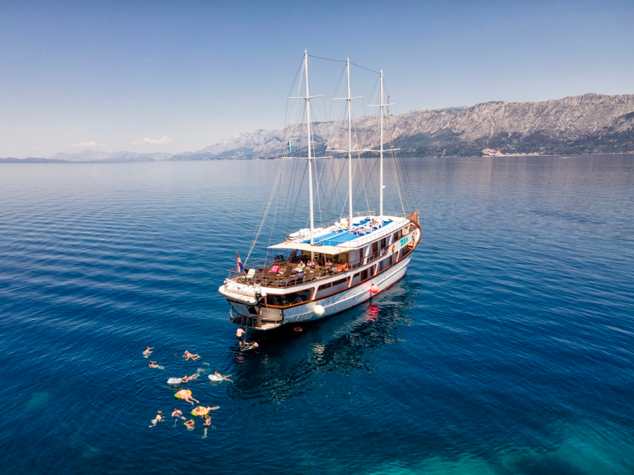 A boat and travellers swimming in the blue ocean in Croatian islands