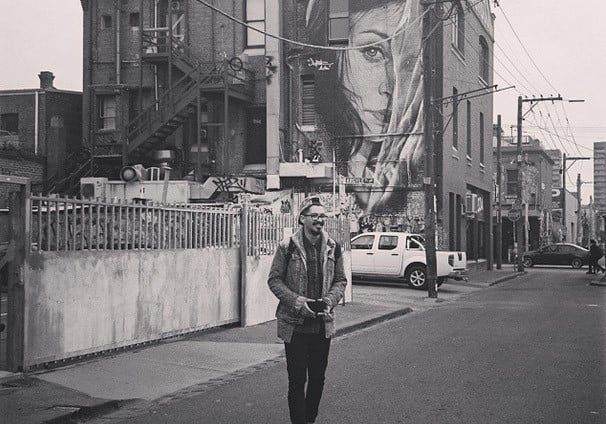 Dan standing on a street in front of a large street art mural in Melbourne