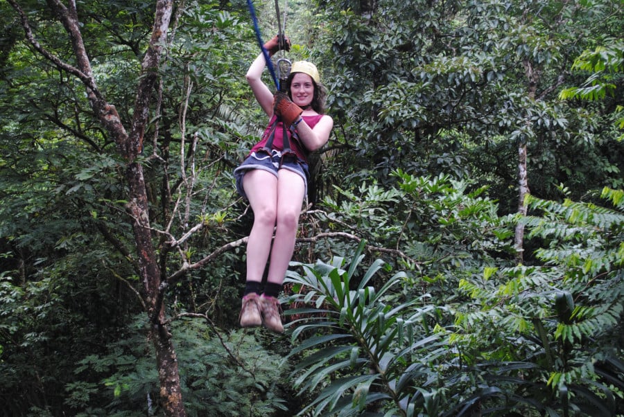 A lady ziplining through a canopy of trees