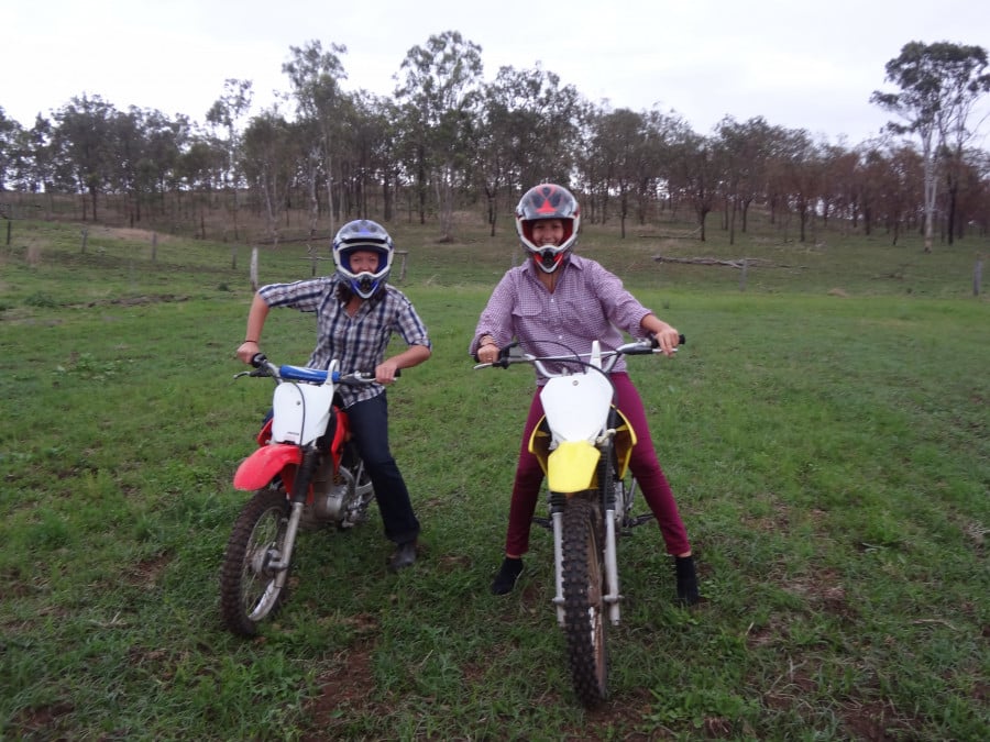Two women on dirtbikes on a ranch in the Australian outback 