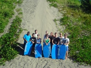 Travellers posing with surfboards on a sandy path