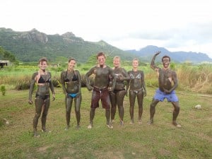 A group of people covered from the neck down in mud