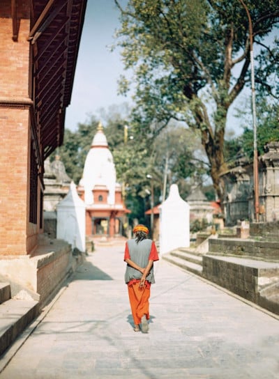 A lady in traditional Nepalese walking down a path next to a monastery