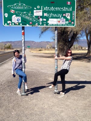 Rachel and a fellow traveller posing below a sign that reads 'Extrarerrestrial Highway'