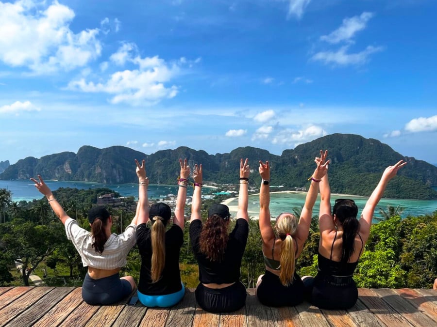 Group of travellers with their hands up at Phi Phi Viewpoint on Koh Phi Phi Island, Thailand 