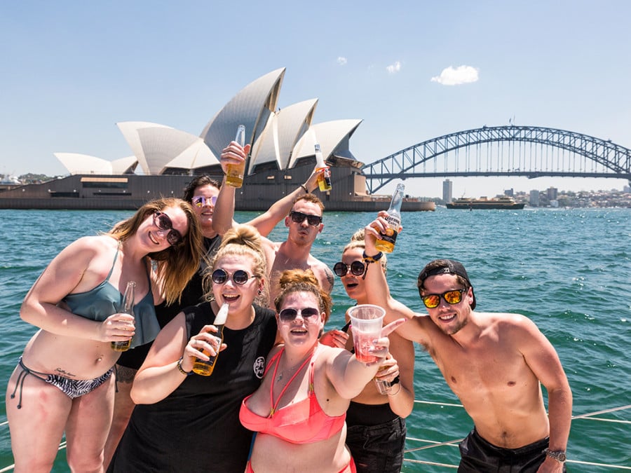 Travellers drinking beers in front of the Sydney Opera House