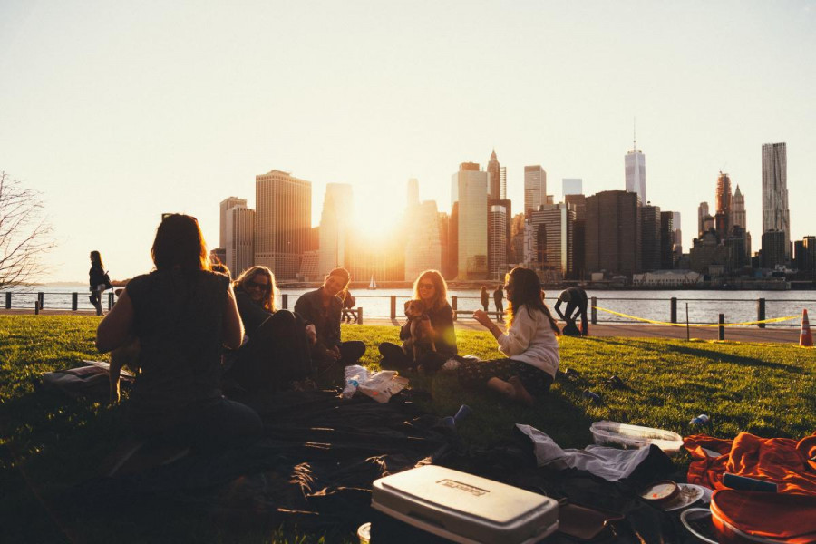 A group of people sitting on a picnic blanket with a city skyline in the background