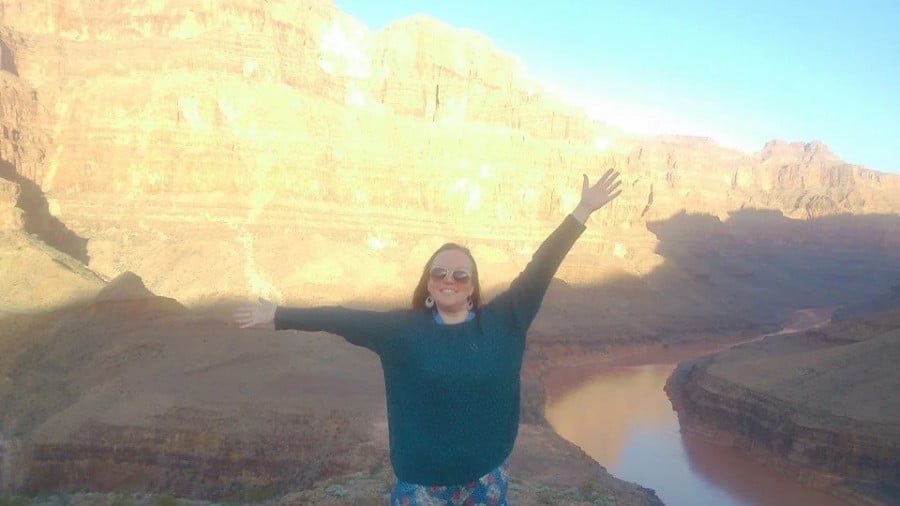 Rachel posing for a photo in front of the Grand Canyon with arms outstretched