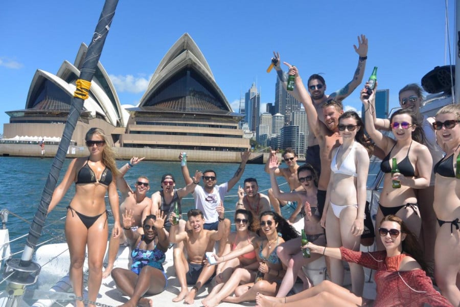 A group of travellers drinking on a boar in front of the Sydney Opera House