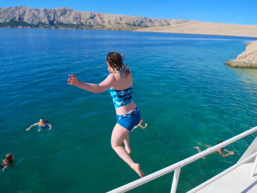 A person jumping from a boat into blue water