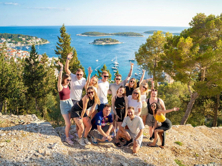 A group of travellers standind on the edge of a cliff overlooking islands and the ocean
