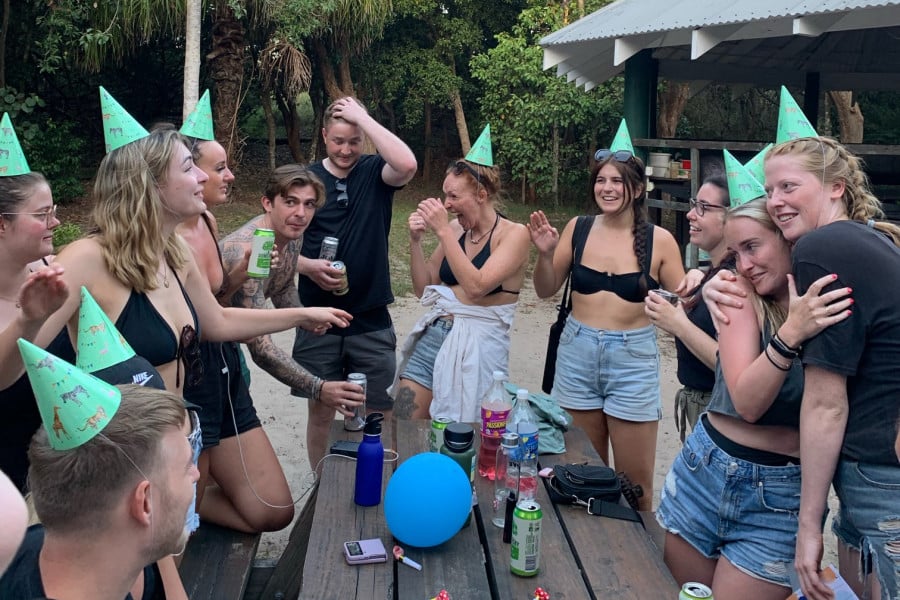 A group of travellers at a table drinking with party hats on
