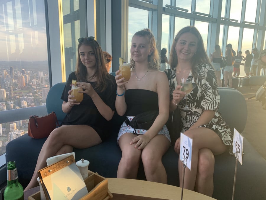 A group of travellers with cocktails in a tower bar with a city skyline view