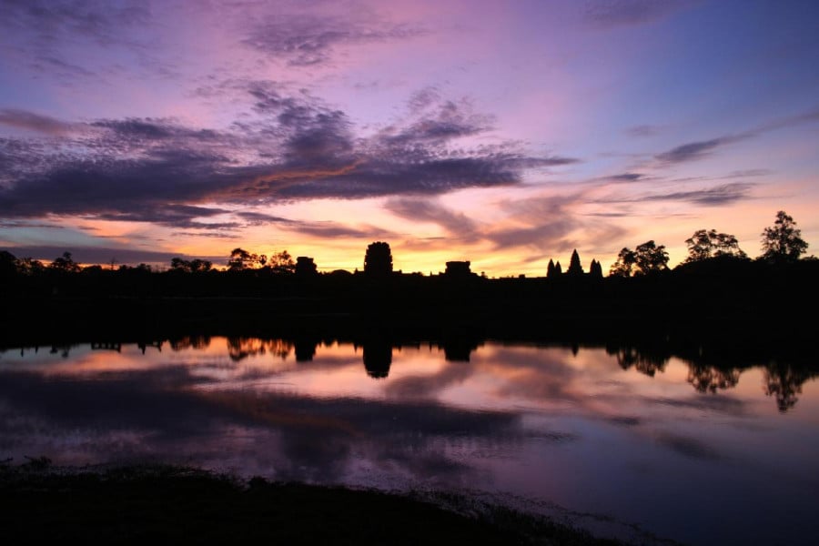 Silhouette of Angkor Wat temple with a purple and orange sunset