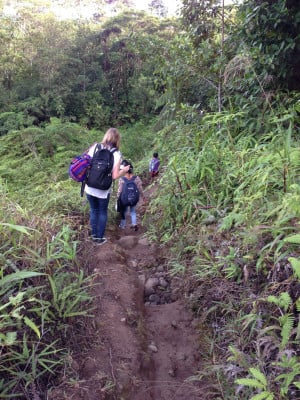 A lady and two children walking through a path in the jungle