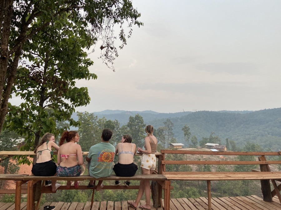Travellers sit on a bench overlooking the jungle