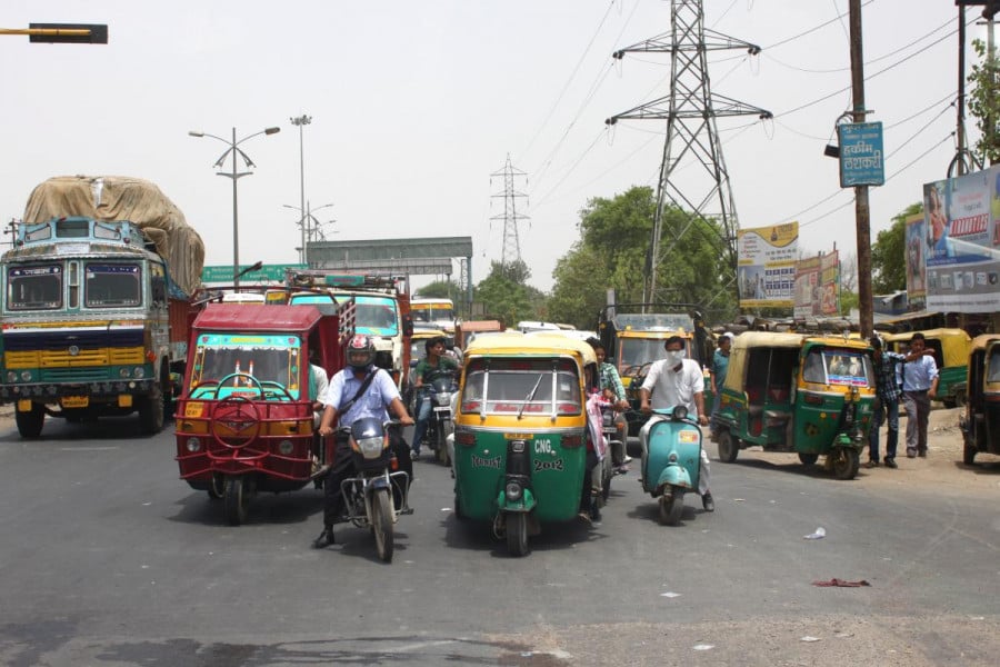 A busy indian road full of people on Tuk-Tuks and scooters