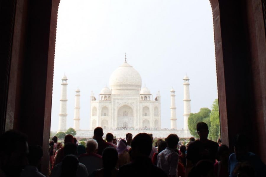 A large crowd in an archway lookin at the Taj Mahal