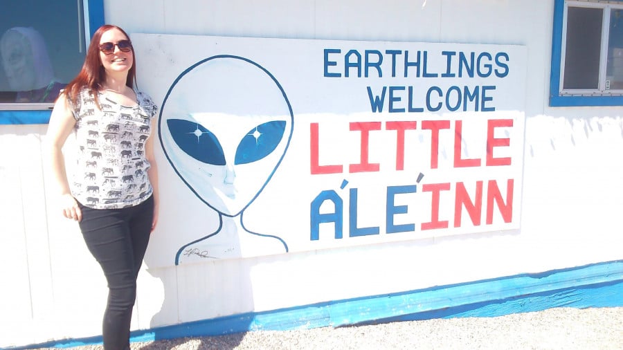 Rachel next to sign with an image of an alien and the text 'Earthlings welcomme little alien'