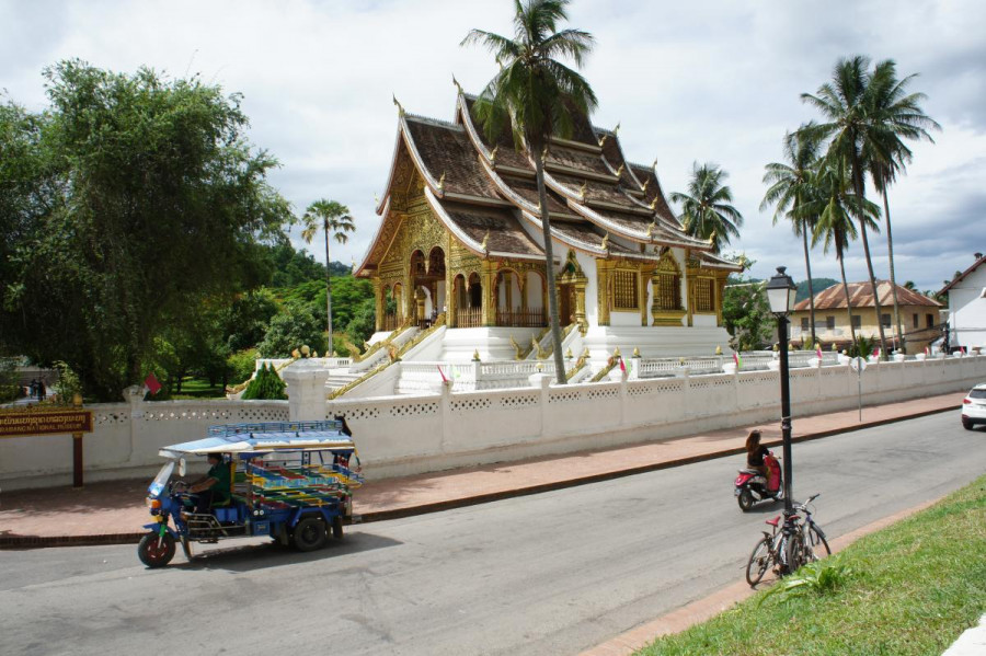 A gold and white temple and nearby road in Luang Prabang