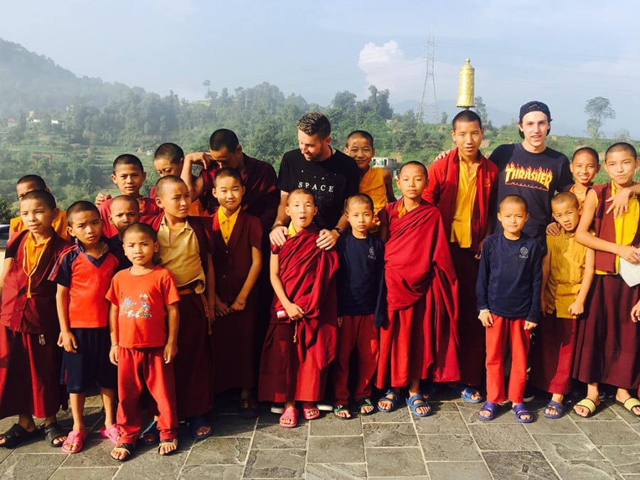 Travellers standing with kids in red monk robes