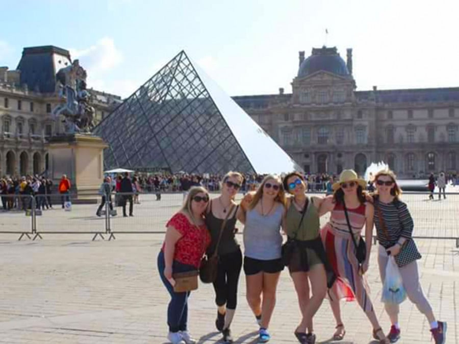 A group of people standing in front of the Louvre