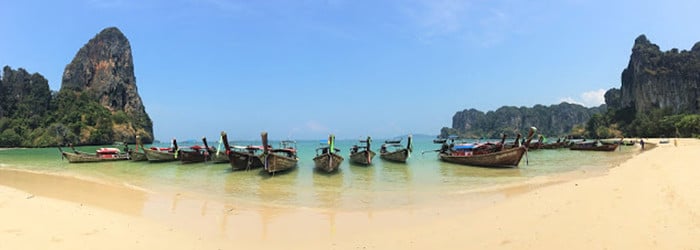 Traditional thai boats with colourful flags lined up on Railay Beach, Thailand
