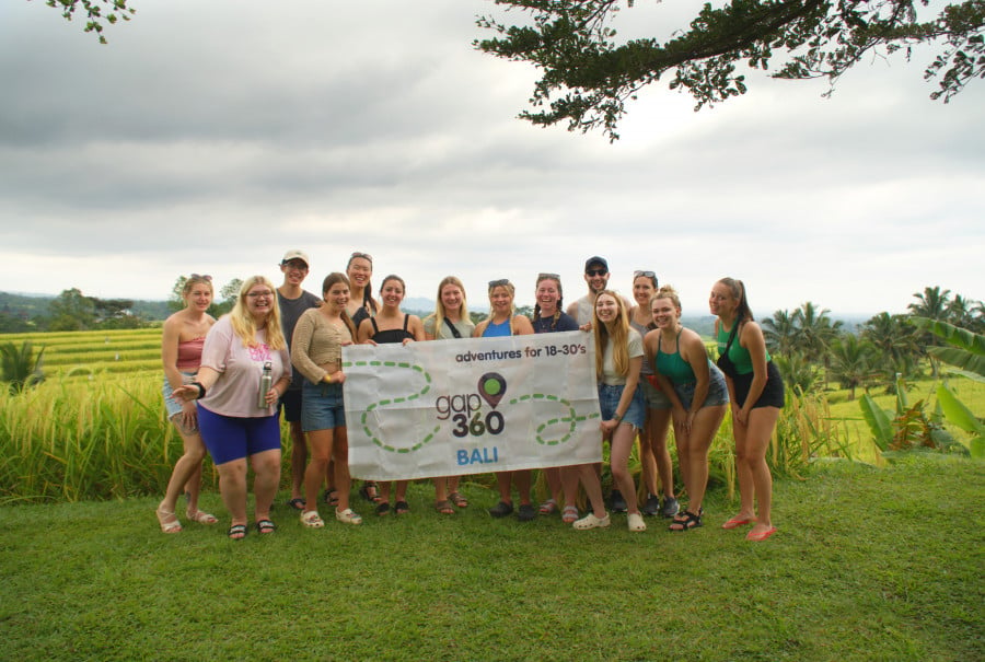 Group travellers holding Gap 360 flag in Jatiluwih Rice Terraces