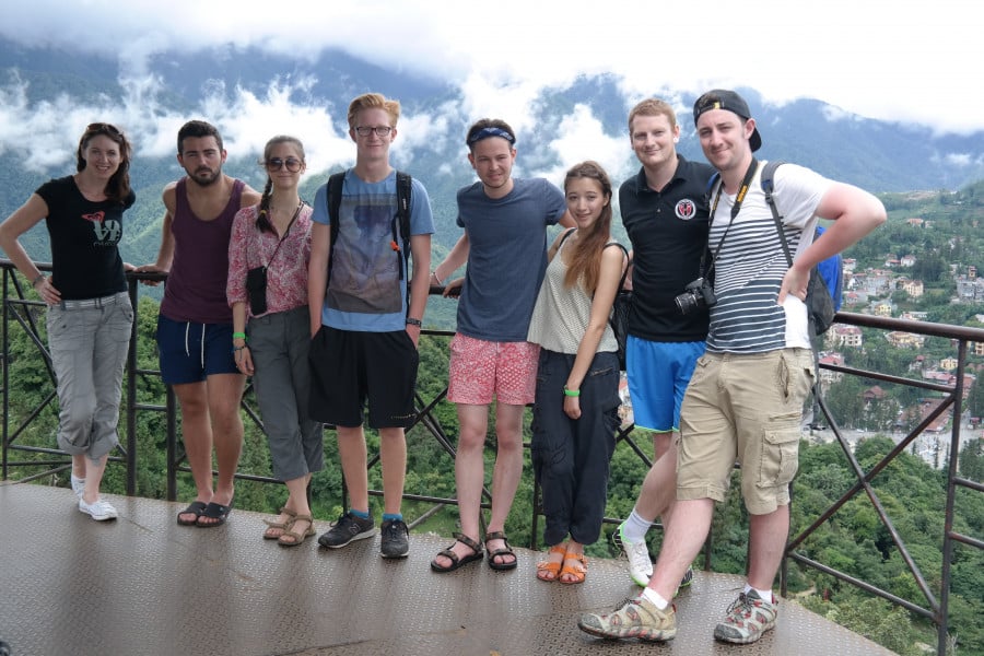 Travellers posing for a photo at a lookout with misty mountains in the background
