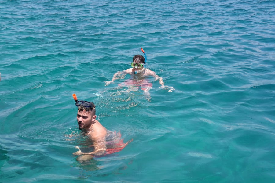 Two people in scuba gear swimming in blue water