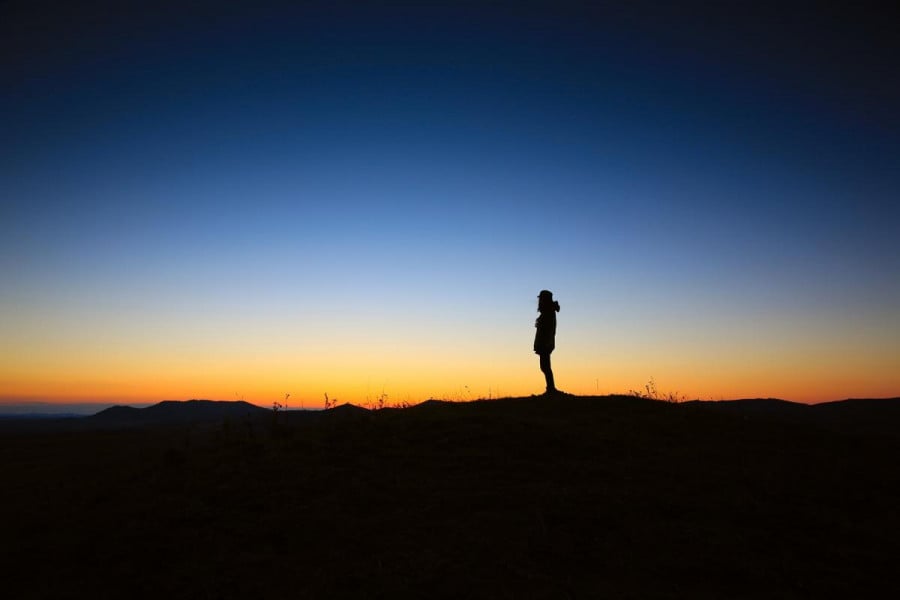 A lone person silhouetted against a sunsetting sky